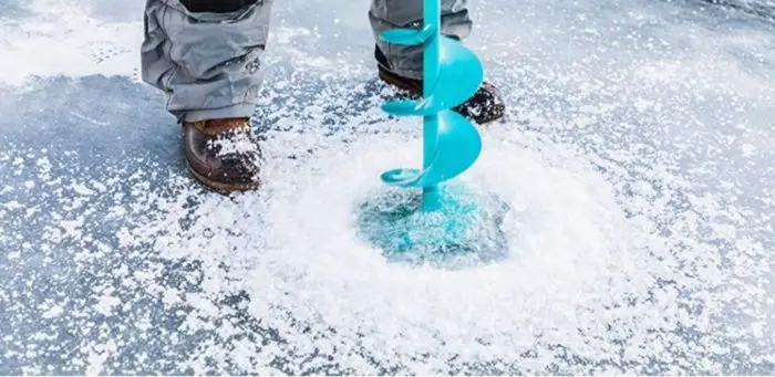 A man drilling a hole using a gas ice auger