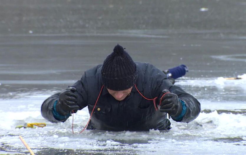 A man using ice picks to get out of water